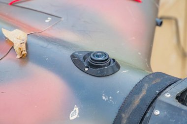 Pas ve toprak egzoz sistemli eski, gri-kahverengi bir tanka yakın plan muhtemelen siyah dairesel bir nesne ve kamera veya sensör pürüzlü doku, sessiz ışıklandırma, gizli stil, açılı perspe