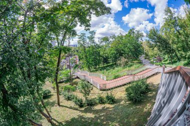 Ağaç, beton yol, bina, kentsel sanat metal parçaları, gökyüzü, çimen, bulut, baca, tuğla cephe, doğal elementler, insan yapımı yapılar, öğleden sonra veya sabah erken saatlerde ışıklandırma