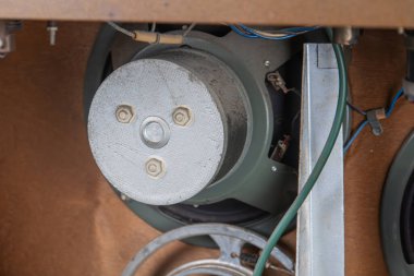 Eski bir metro radyosunun kablo ve kablolarla çevrili bir metal teçhizat ya da sproketin merkezi odaklı bölümünün yakın görüntüsü yukarıdan, ağırlıklı olarak metalik renkte aydınlatılıyor.