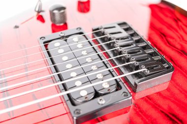 Canlı kırmızı elektro gitar başlığının yakın plan görüntüsü, belirgin siyah donanım ve gümüş ayar çivileri ile siyah ahşap tahıl tanecikleri karşı siyah pikap ve gitar boyun, görünür