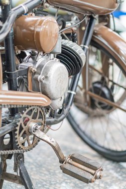 Klasik motosiklet, yan görünüm kahverengi motor, metal bileşenler, büyük yuvarlak far, iki küçük ışık, kahverengi çamurluk, yastıklı koltuk, klasik tasarım elementleri, nötr ışıklandırma, ortam