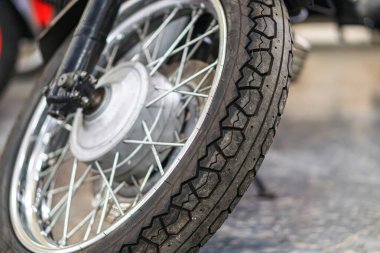 Antika motosiklet tekerleğinin yakın plan görüntüsü, karmaşık tellerin görüntüsü ve off-road kullanımı için derin lastik izleri yukarıdan gelen yön aydınlatması gölgeler, derinliği ve dokuyu yükselten Rea