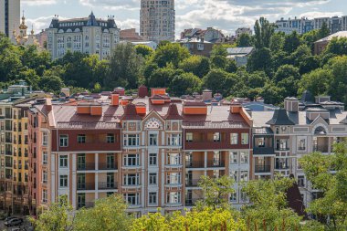 Avrupa 'nın eski bir kentindeki klasik, çok katlı beyaz konut binalarının yakın görüntüsü yeşillik ve açık gökyüzünü de kapsıyor. Akşamüstü aydınlatma yok.