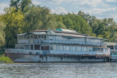Büyük, beyaz yolcu feribotu... sakin sulara demirlemiş... nehir ya da büyük göl... beyaz gövde, karanlık çatı, sayısız pencere... uzun yolculuklar için fonksiyonel ve konforlu olduğunu gösteriyor.