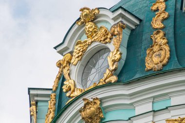 Eski bir Avrupa şehrinin büyük, kubbeli mimari yapısının yakın plan görüntüsü yapıda altın bir kubbe, karmaşık altın süslemeler ve beyaz bir cephe bulunur.