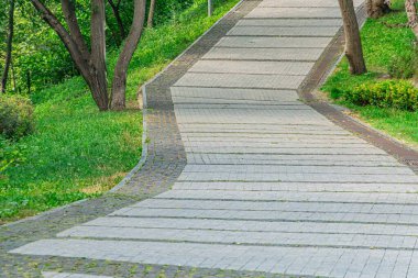 Modern bir şehirde, yaprakların arasından süzülen, yaprakların arasından süzülen ve gölgeler bırakan gri kiremitlerden inşa edilmiş yemyeşil bir bahçe yolu.