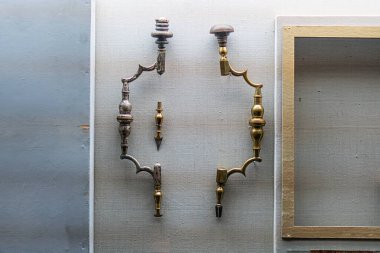 Gri, eğimli bir duvara antika banyo armatürleri saplı ve kaydırmalı üç musluk iki tane elsiz musluk tasarlıyor muhtemelen pirinç ya da bronz kenarlı dikdörtgen ayna ve altın kenarlı.