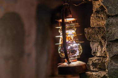 Yosun tutmuş bir yeraltı tünelinde eski bir pirinç lamba, tepesinde de bir yağ yakıcı var.