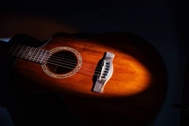 Karanlık bir akustik gitarın yakın plan görüntüsü, odaklanmış ışıklandırma, perdeler, teller, yaratıcı müzik temaları caz, blues, rock