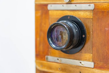 Eskici kamera, açık arkaplana karşı, büyük lens, çoklu halka, koyu beden muhtemelen siyah ya da koyu kahverengi, metal bileşenler, film ilerlemesi düğmesi, mat bitiş, metin ya da marka yok, hatta açık renk bile yok.