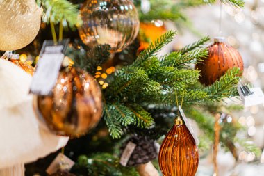 Kırmızı, altın ve gümüşle süslenmiş büyük bir Noel ağacı ile kapalı bir ortam. Ağaç çeşitli boyutlarda küresel süslemelerle süslenmiş, bazıları etiketlenmiş. Ağacın tepesi ise...