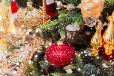 Şenlikli, süslenmiş, kırmızı ve altın süslemeli Noel ağacı, ışıltılı desen, sıcak aydınlatma, yemyeşil dallar, görüntünün derinliği, yukarıdan bakış açısı, keskin odaklanma.