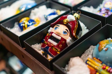 Üniformalı asker şeklinde detaylı bir Noel ağacı süslemesi. Yastık köpüğüyle birlikte siyah bir kutuda sergileniyor. Arka planda görülen diğer sessiz Noel süsleri.