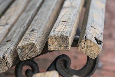 Yıpranmış ahşap kalasların yakın çekimi, muhtemelen şehir banklarından veya masa üstlerinden, kentsel bir çevrede L şekli oluşturuyorlar.