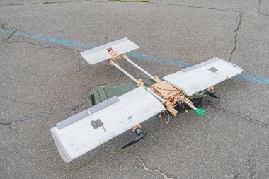 Çatlamış ve lekeli beton bir yüzey üzerinde dikey kanatları olan bir Rus İHA 'sı. Düz inşaat, takip kenarındaki kontrol yüzeyleri, sivri kanat uçları, commu için anten.