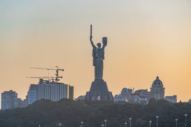 Kyiv Anavatanı Anıtı, Rio de Janeiro 'da Sunset' e karşı İsa Mesih, vinçler, inşaat, turuncu ve mavi gökyüzü geçişi, siluet şehir manzarası, parıldayan bina ışıkları, gece gündüz