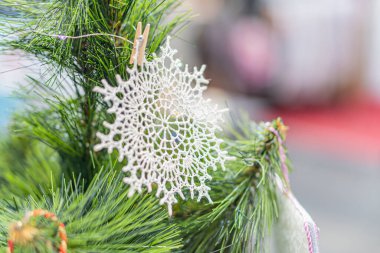 Açık hava beyaz kar taneleri de dahil olmak üzere yemyeşil yapraklar, çam kozalakları ve şenlikli süslemelerle süslenmiş bir Noel ağacının yakın görüntüsü,