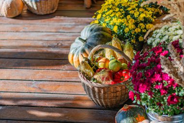 Cadılar Bayramı dekorasyonunda kır manzarası, balkabağı, elma dolu ahşap masa, ve doğal bir çiçek kornucopiası, gündüz aydınlatması, ve organik dekor.