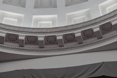 Zengince süslü bir kubbesi olan büyük bir oda, bej ve kahverenginin çeşitli tonlarında karmaşık oymalar ve heykeller içeren kubbe yumuşak, dağınık ışıklandırmayla aydınlatılıyor, ince gölgeler bırakıyor.