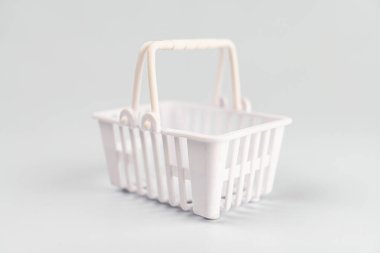 Açık gri bir yüzey üzerinde, tepedeki ışık kaynağının altında iki kırmızı sepetin olduğu minimalist sahne