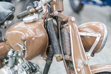 Krom aksanlı klasik kahverengi motosiklet, kısmen açık motor, sağlam çerçeve, ahşap arka plan, yumuşak ışıklandırma, garaj veya sergi odası ayarları