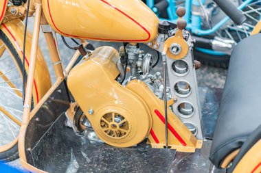 İyi bakımlı klasik bir motosikletin yakın çekimi, kırmızı ve siyah aksanlı zengin, kısmen gri zeminde iki motorsikletle çevrili.