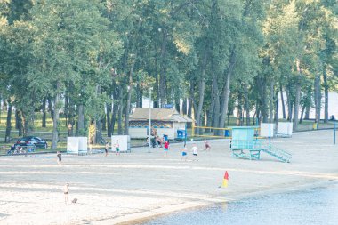 Kyiv, Ukrayna 'daki hareketli bir plajın dikey manzarası arasında su sporları, sosyalleşme, çocuk oyunları ve sıcak Kyiv, Ukrayna 06-26-2025 ile kayık renkleri yer alıyor.