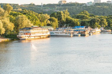 Kyiv, Ukrayna kıyısı sahnesi gün doğumunda ya da batımında büyük bir yüzen ev ile iskele etrafına ve ba Kyiv, Ukrayna 06-26-2025