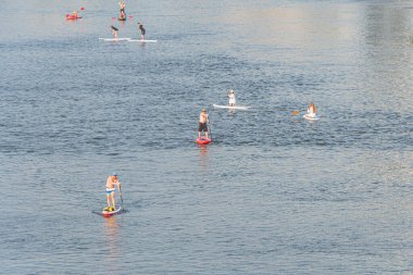 Ayakta raket ve kano gibi çeşitli su aktivitelerinin yer aldığı sakin bir su manzarası, gün ışığında sakin bir su kütlesi altında Kyiv, Ukrayna 07-04-2025