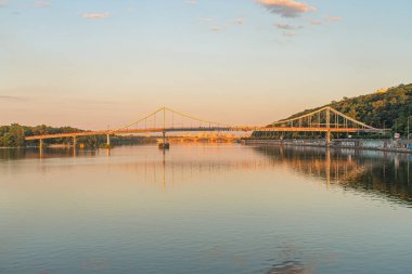 Ukrayna 'nın başkenti Kyiv' deki sakin su üzerindeki köprü, günbatımı arkaplanı Kyiv, Ukrayna 07-05-2025