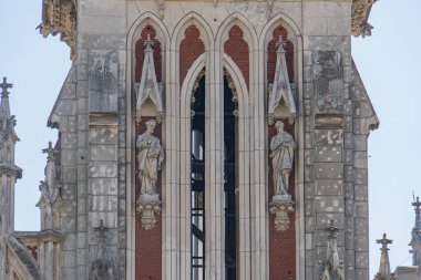 Kyiv 'deki Aziz Nicholas Katolik Kilisesi' nin uzun taş kulesi, sivri kemerler, dekoratif unsurlar, pencereler, heykeller, Kyiv, Ukrayna 07-06-2025 ile Gotik mimari ayrıntılara sahip.