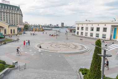 Kyiv, Ukrayna 'daki rıhtım manzarası dairesel çeşme, kırmızı tuğla kaldırım, mavi ve beyaz binalar, canlı renkler, hareketli kalabalık Kyiv, Ukrayna 07-06-2025