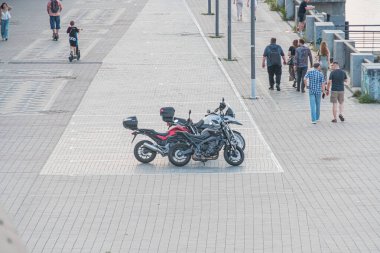 Ukrayna, Kyiv 'deki tuğla kaldırıma yakın çekim, su yoluna çıkıyor. İki canlı motosiklet kırmızı ve siyah, parlak siyah, sağa bakan arka plan büstü Kyiv, Ukrayna 07-06-2025