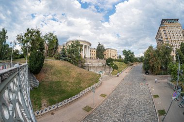 Bulutlu Kyiv şehir manzarası, tarihi mimari, klasik cephe, asfaltlı yol, manikürlü yol, karmaşık tasarımı olan metal korkuluk, yumuşak ışıklandırma, toprak rengi pa Kyiv, Ukrayna 07-13-2025