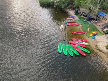 Kyiv 'de tekneleri, doğal manzarası ve mavi renkleri yansıtan sakin nehir kıyısı. Renkli kanoyla kaplı sakin su, eski Kyiv, Ukrayna 08-17-2025