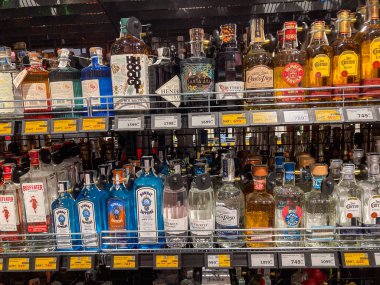 Bir içki dükkanında iyi düzenlenmiş, çeşitli alkol şişelerini gösteren kehribar rengi, koyu mavi renkli etiketler ve kapaklar CI Kyiv, Ukrayna 06-30-2025
