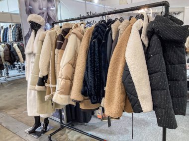 Dıştaki kürk kaplı ceketlerin, kabarık ceketlerin, çeşitli renklerde kış giysilerinin, kapalı alanda beyaz bir duvara karşı görüntüsü, Kyiv, Ukrayna 07-31-2025