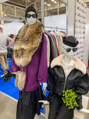 Biri uzun etekli, kürklü ve mor düğmeli olmak üzere katmanlar giyen iki mankenin sergilendiği kapalı moda sergisinde Kyiv, Ukrayna 07-31-2025
