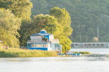 Kyiv, Ukrayna 'da göl kenarındaki eski kayıkhane Sıcak gün batımı ya da durgun göl suları ile gündoğumu sahnesi altın ışıklı ahşap iskele, küçük tekne, yemyeşil çimen, Kyiv, Ukrayna 06-26-2025
