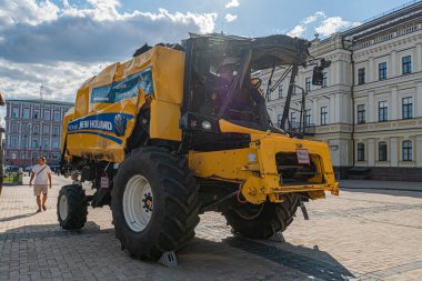 Şehir ortamında yükleyici ve spreyli sarı traktör, kaldırım taşı zemin, tarihi mimari, püskürtücü tankında gübre metni, gündüz vakti, Kyiv, Ukrayna 07-05-2025 'i gören kimse yok.