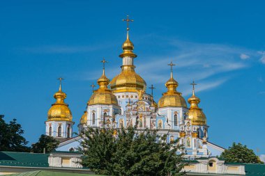 Ukrayna 'nın başkenti Kyiv' deki mavi Ortodoks katedrali, güneş ışığıyla yıkanmış, altın aksanlarla süslenmiş ve ön planda Kyiv, Ukrayna 07-05-2025 'te büyük bir yeşil kubbe tarafından yönetiliyor.