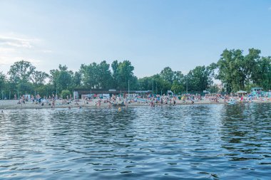 Kyiv, Ukrayna 'daki sahil manzarası. Mavi gökyüzünü beyaz bulutlarla yansıtan sakin okyanus. İnsanlar, botlar küçük, dinleniyor, palmiye ağaçları kumlu sahil şeridi Kyiv, Ukrayna 07-12-2025