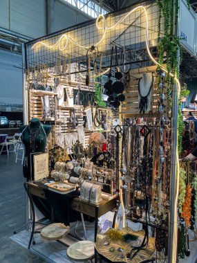 Sağlam bir metal çerçeve ve ağ dış yüzeyiyle inşa edilmiş, bir etkinlikte veya sergide canlı mücevher standı ahşap bir masa, sergilenen kolyeler, Kyiv, Ukrayna 07-31-2025