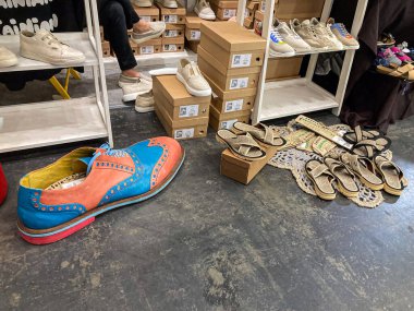 Yerlere saçılmış çeşitli ayakkabılar içeren bir ayakkabı mağazasının fotoğraf sergisi, aralarında mavi tabanlı canlı bir çift ve turuncu yükseltici kutular, farklı Kyiv, Ukrayna 07-31-2025