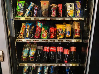 Ukrayna 'da iyi stoklanmış bir buzdolabı otomatında çeşitli abur cubur ve içecekler sergileniyor. İçerisi ışıklandırmayla bile aydınlatılıyor. C Kyiv, Ukrayna 07-02-2025