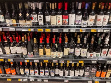 Şarap deposu vitrininde çeşitli etiketli şişeler var, sıra sıra dizilmiş, tıpa tıpaları ile kaplanmış hafif gölgeler aydınlatma ile shel Kyiv, Ukrayna 07-02-2025 derinliği vurgulanıyor