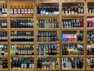 Ukrayna, Kyiv, Ukrayna 07-03-2025 'te ahşap raflarda düzenlenmiş çeşitli şişelerle dolu loş bir içki deposu vitrini.