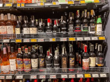 Kyiv, Ukrayna 07-12-2025 mağazasında derinlik yaratmak için sırayla dizilmiş çeşitli renk ve boylarda şarap şişeleriyle dolu süpermarket vitrinleri.