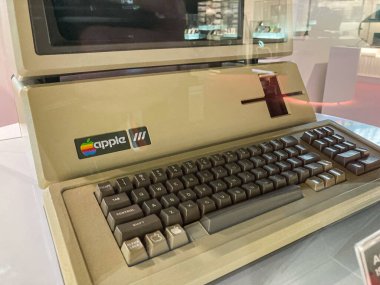 Müzede veya galeride sergilenen klasik Apple bilgisayarı, izleyiciyle yüzleşmek için açılı Karanlık klavye, açık renkli vücut, eski moda Apple logosu görünür Kyiv, Ukrayna 07-13-2025