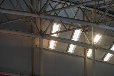 Geniş, açık sanayi alanı, yüksek tavanı, çoklu çelik kirişleri, sütunları ve tavan pencereleri modern tavan penceresi tasarımlı, beton ya da çelik duvarlı, temiz zemin yüzeyi yok.